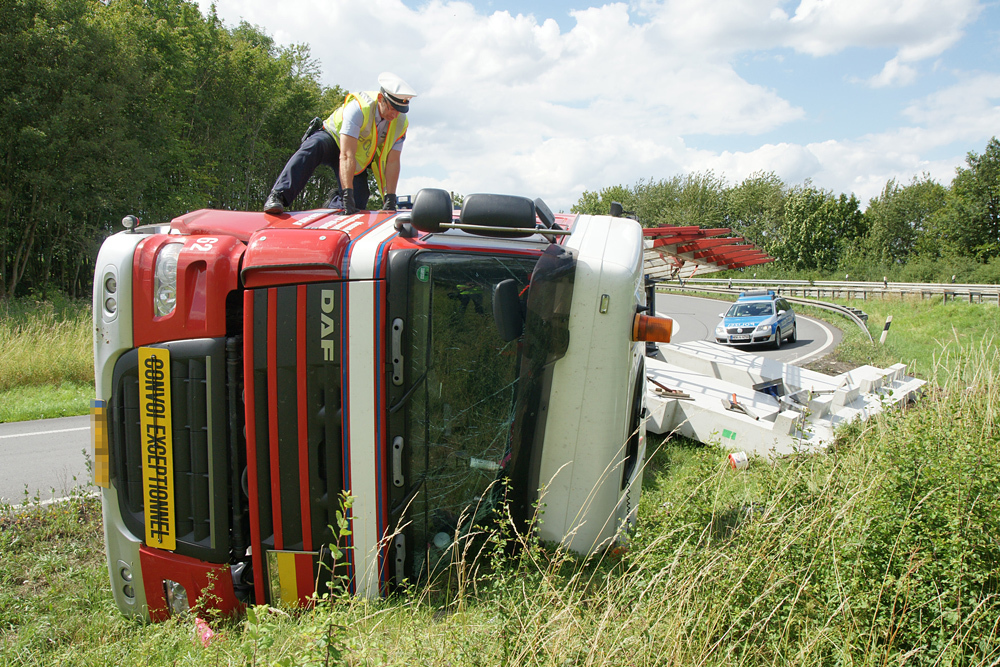 Ein Polizist sichert Spuren am umgestürzten Schwertransporter.