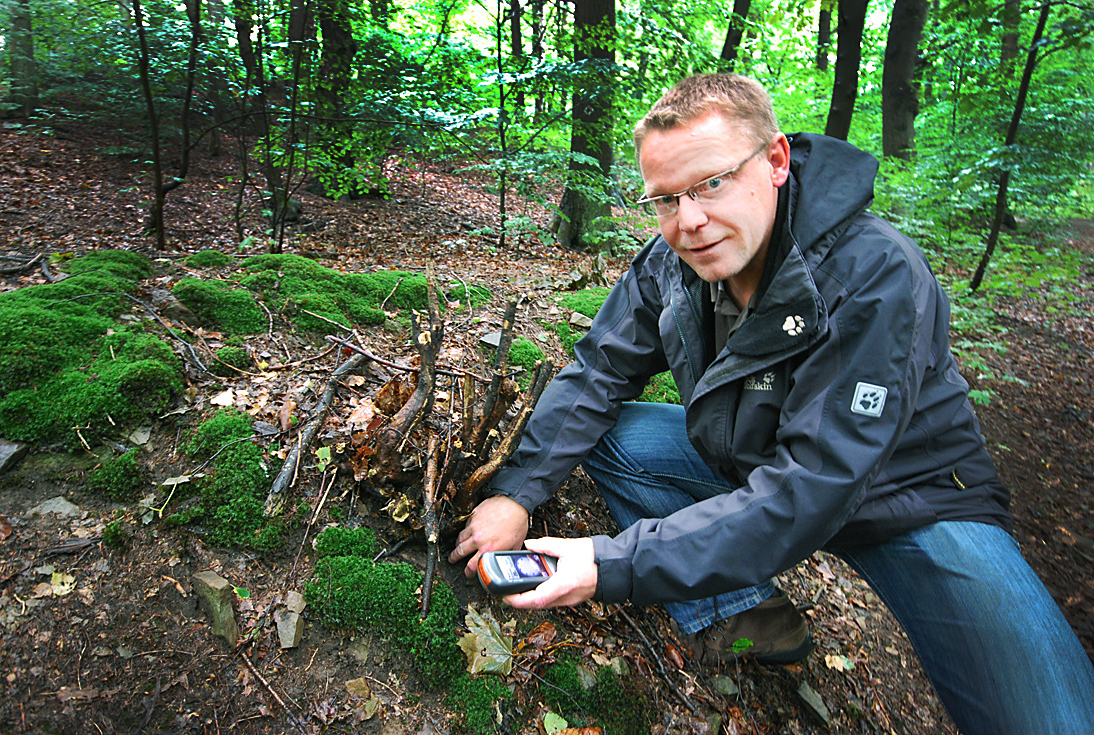Oliver Götte zeigt, was zum Geocaching dazugehört: GPS-Gerät, eine Plastikdose als moderne Schatzkiste, gefüllt mit kleinen Überraschungen und mit einem Logbuch. Foto: Schneidersmann