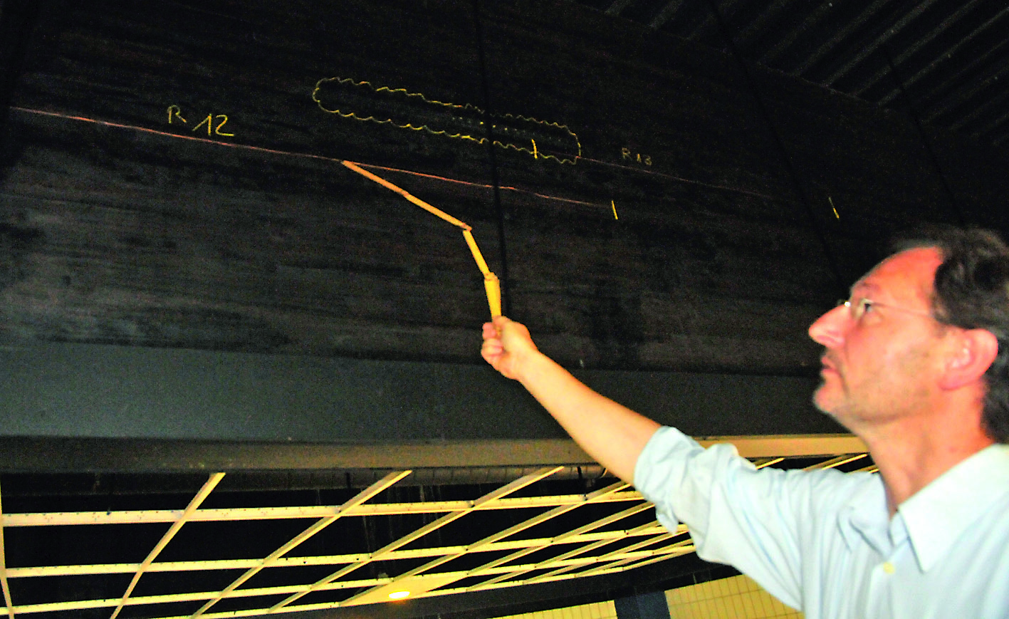 Architekt Waldemar Madeia zeigt einen Riss in einem der 30 Meter langen Holzleimbinder.