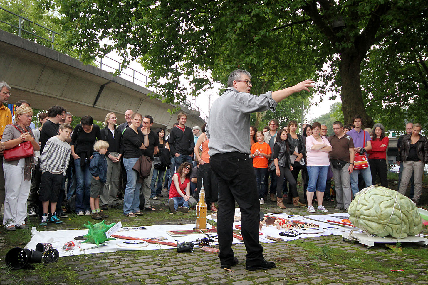 Künstler Matthias Schamp erläutert sein Projekt: „Einfach so“ flogen die Kunstwerke Sonntag über den Zaun der Brache. Foto: Molatta