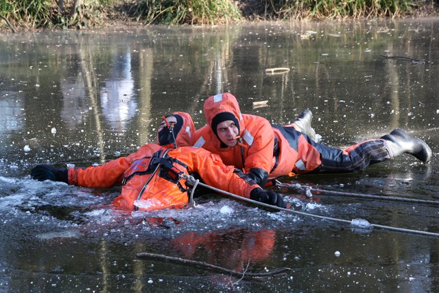 Ein Feuerwehrmann robbt auf dem Bauch zum Opfer, zieht den "Bewusstlosen" aus dem Eisloch.