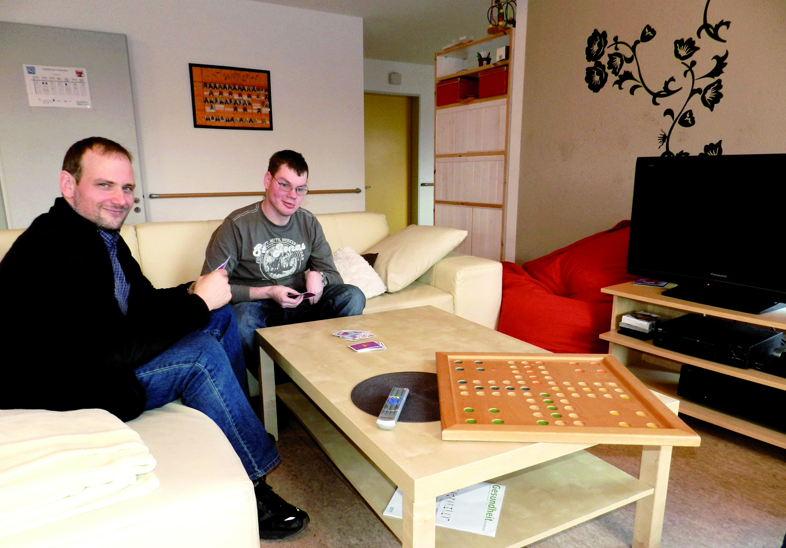 Wohnstätten-Leiter Peter Leidig mit Bewohner Fabian Steber im Gemeinschaftsraum beim gemeinsamen Kartenspiel.