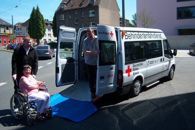 Fahrdienstleiter Markus Eisenhuth mit einem Fahrgast und DRK-Vorsitzender Thorsten Junker präsentieren einen neuen Behindertentransporter.