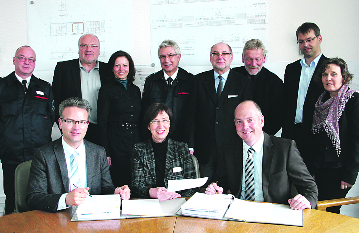 Die Unterzeichnung der Verträge für die Feuer- und Rettungswache am Wildhagen: (hinten v.l.) der stellvertretende Feuerwehrchef Thomas Gerk, Rudolf Viefhaus, Heike Harnisch (beide Projektleiter vom Fachbereich Gebäudewirtschaft), Feuerwehrchef Jürgen Rabenschlag, Fachbereichsleiter Gerhard Rohde, Heinz Spitzbart (Büro kPlan, Generalplaner und Projektsteuerung), Lars Kruel, Monika Körner-Downes (beide List-Bau) und vorne (v.l.) Dr. Frank Burbulla, Dr. Dagmar Goch und Jens Grüner (List-Bau).Foto: Römer
