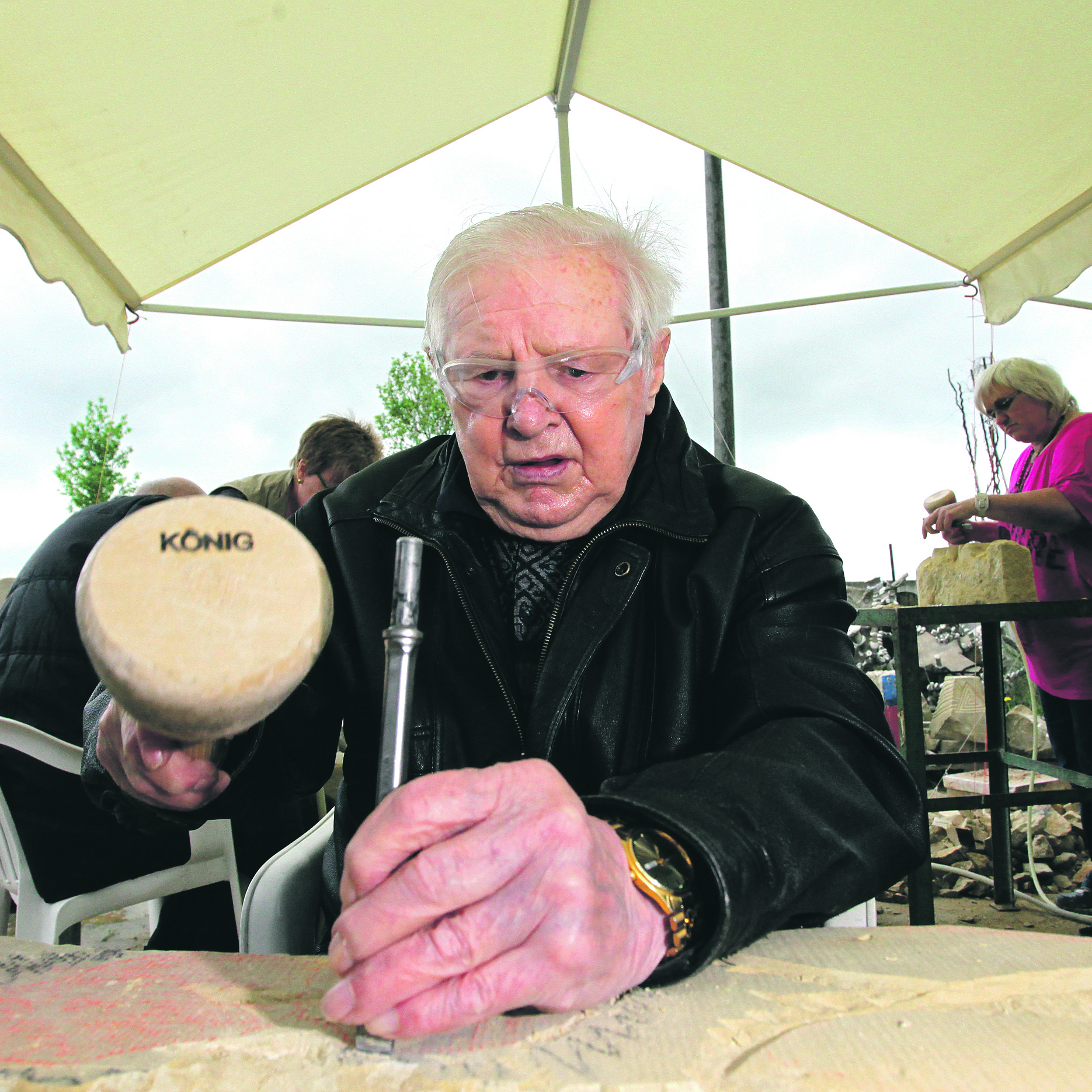 Volle Konzentration: Bernie Bross hat Knüffel und Schlageisen in den Händen. Vor ihm liegt ein 40 Kilo schwerer Sandstein, aus dem ein Schmetterlingsfries werden soll.