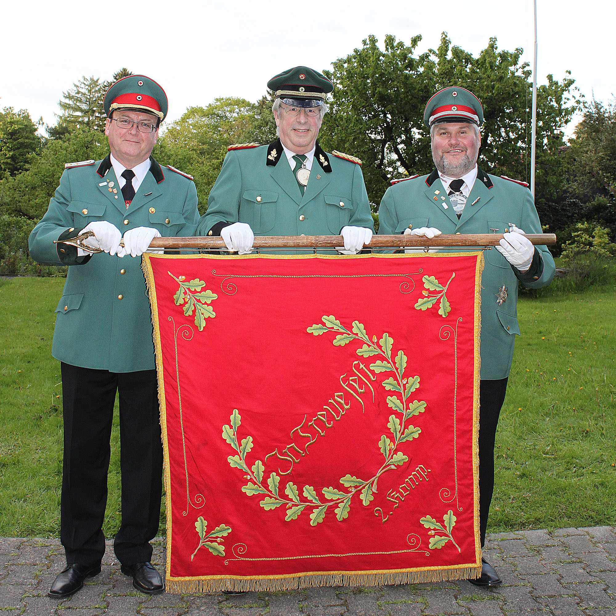 Fahnenübergabe durch Oberst H.-D. Petereit (Mi.) von Bernhard Hertel (li.) an neuen Kompaniechef Volker Tennie (re.) in der Gartenanlage IS-Wermingsen