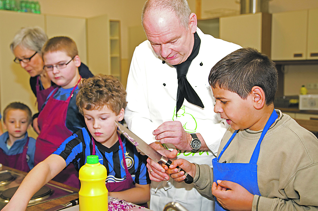 Niklas (7), Ingeborg Dierkes (Betreuerin), Justin (9), Alexander (8), Koch Michael Schläfke und Lavdim (10) beim Zubereiten der Mahlzeit.Foto: Kosjak