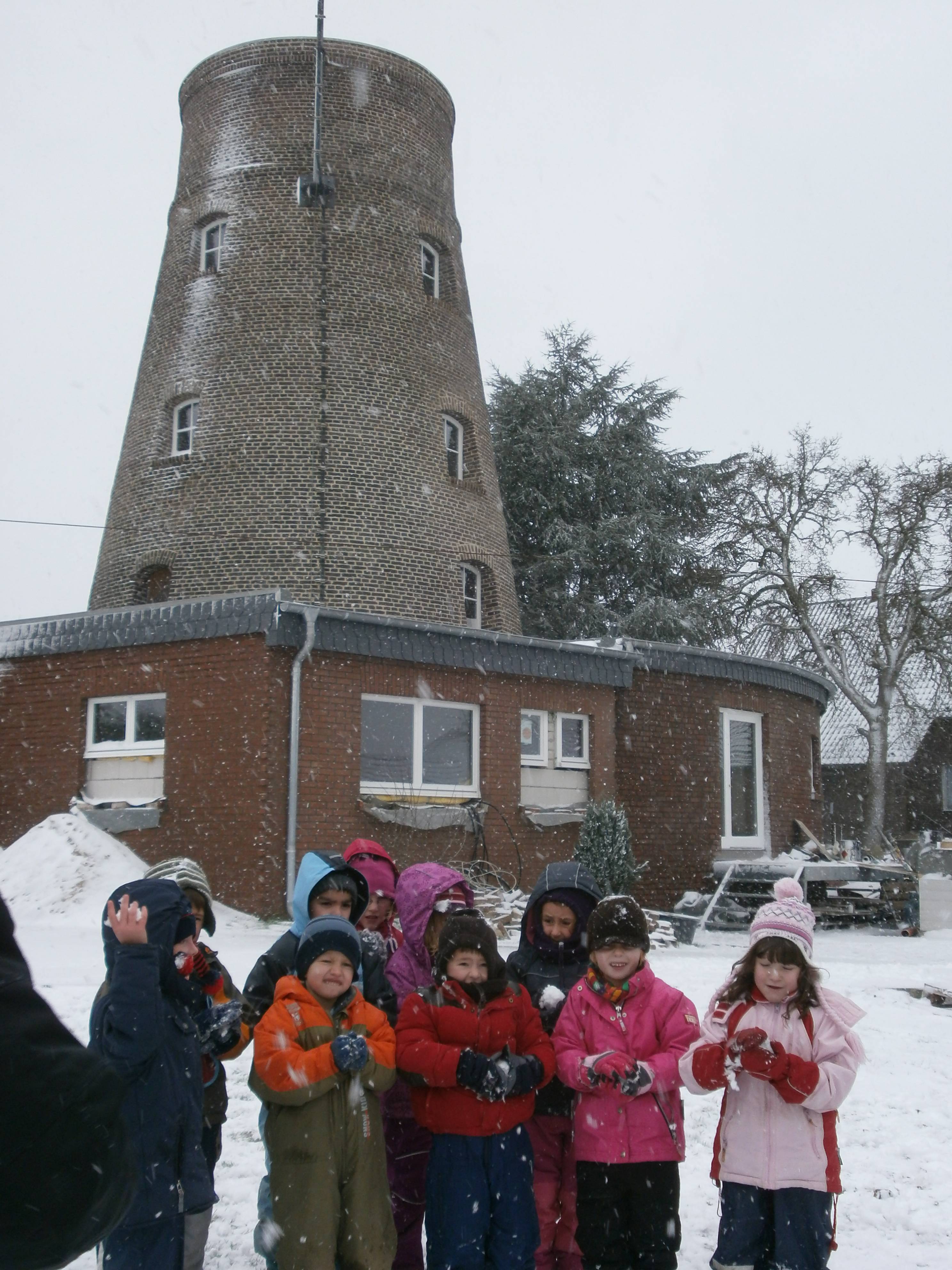 Schneebegeisterte Mühlenbergkinder vor der restaurierten Mühle