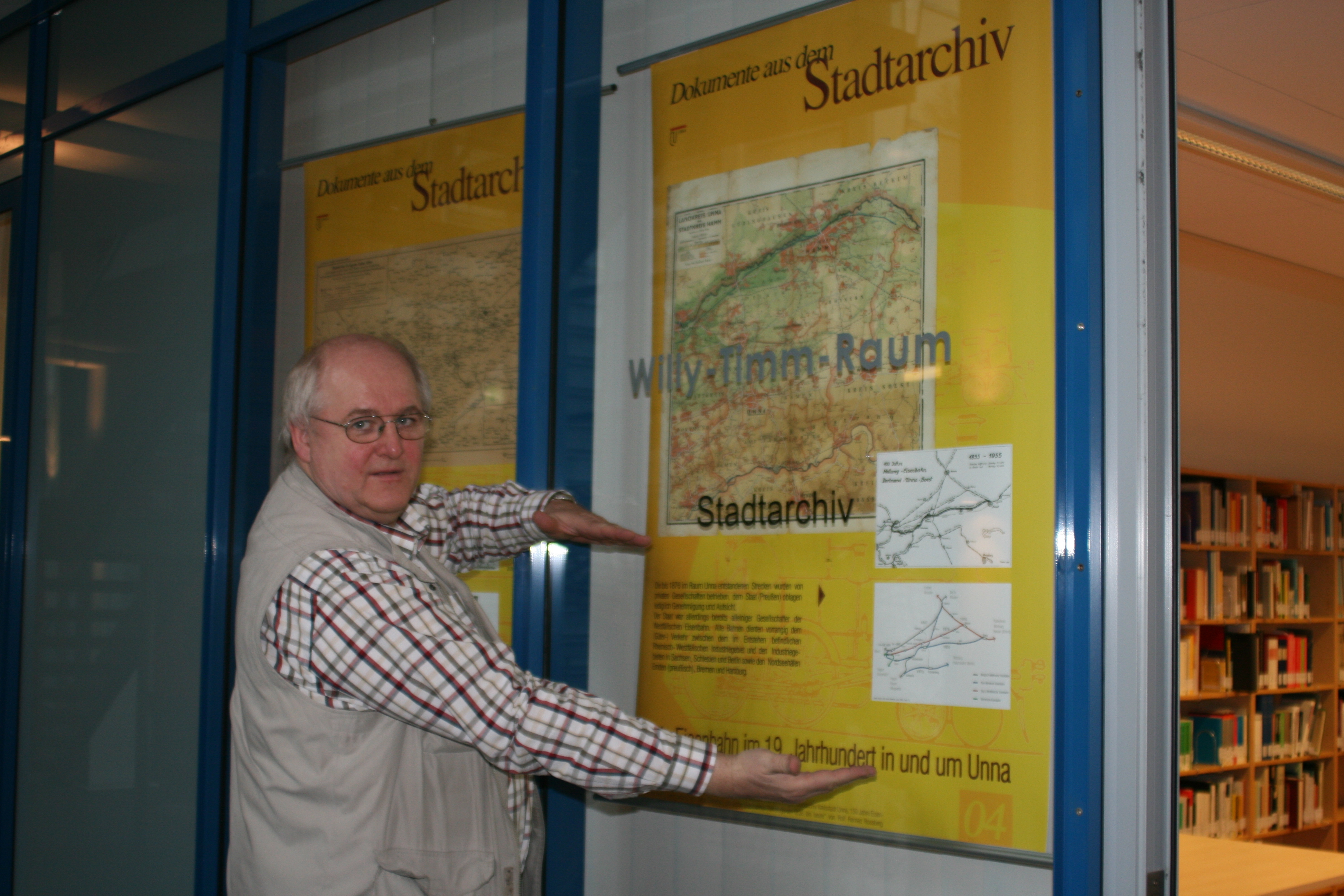 So wie diese Poster werden ab kommendem Jahr die Kalenderblätter zur Unnaer Geschichte in den Fenstern des Stadtarchivs hängen. Thomas Wardenga zeigt, wo sich im unteren Drittel das Kalendarium befinden wird.