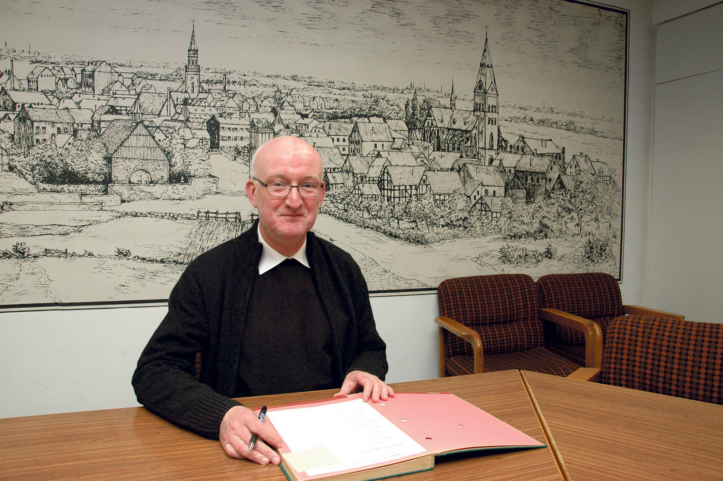 Propst Werner Plantzen vor historischem Hintergrund, einer alten Stadtansicht von Wattenscheid.