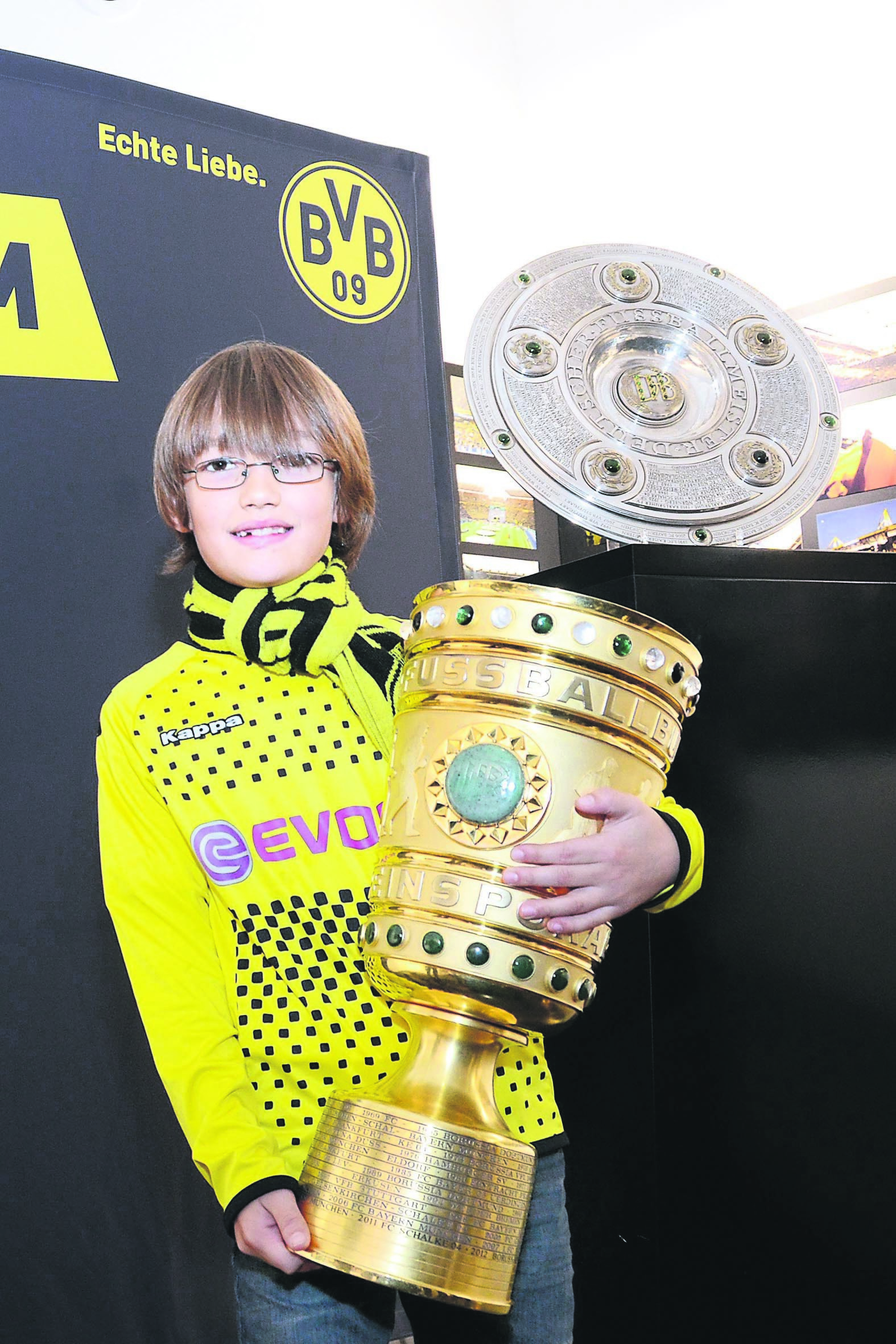 Lukas im Borusseum mit dem Pokal vor der Schale.