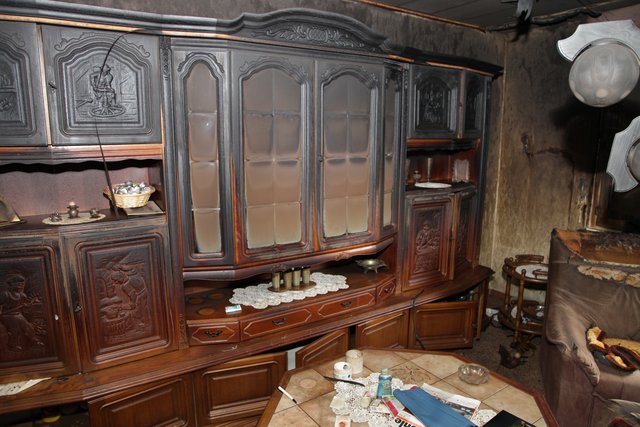Blick ins Wohnzimmer. Die Spuren von Feuer und Rauch zeichnen sich an Schrank und Wänden ab. | Foto: Magalski