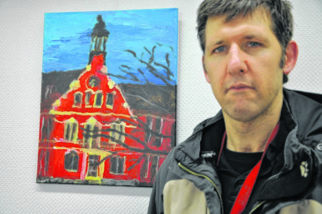 Der Künstler und seine Darstellung des Werdener Rathauses. Zu sehen sind Johannes Beeses Bilder derzeit in einer Ausstellung in einer Altenessener Arztpraxis.