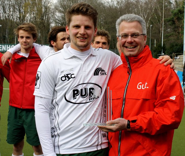Sparkassen-Chef Martin Weck überreicht dem Mannschaftskapitän vom Crefelder HTC, Felix Klein den Siegerpokal.
