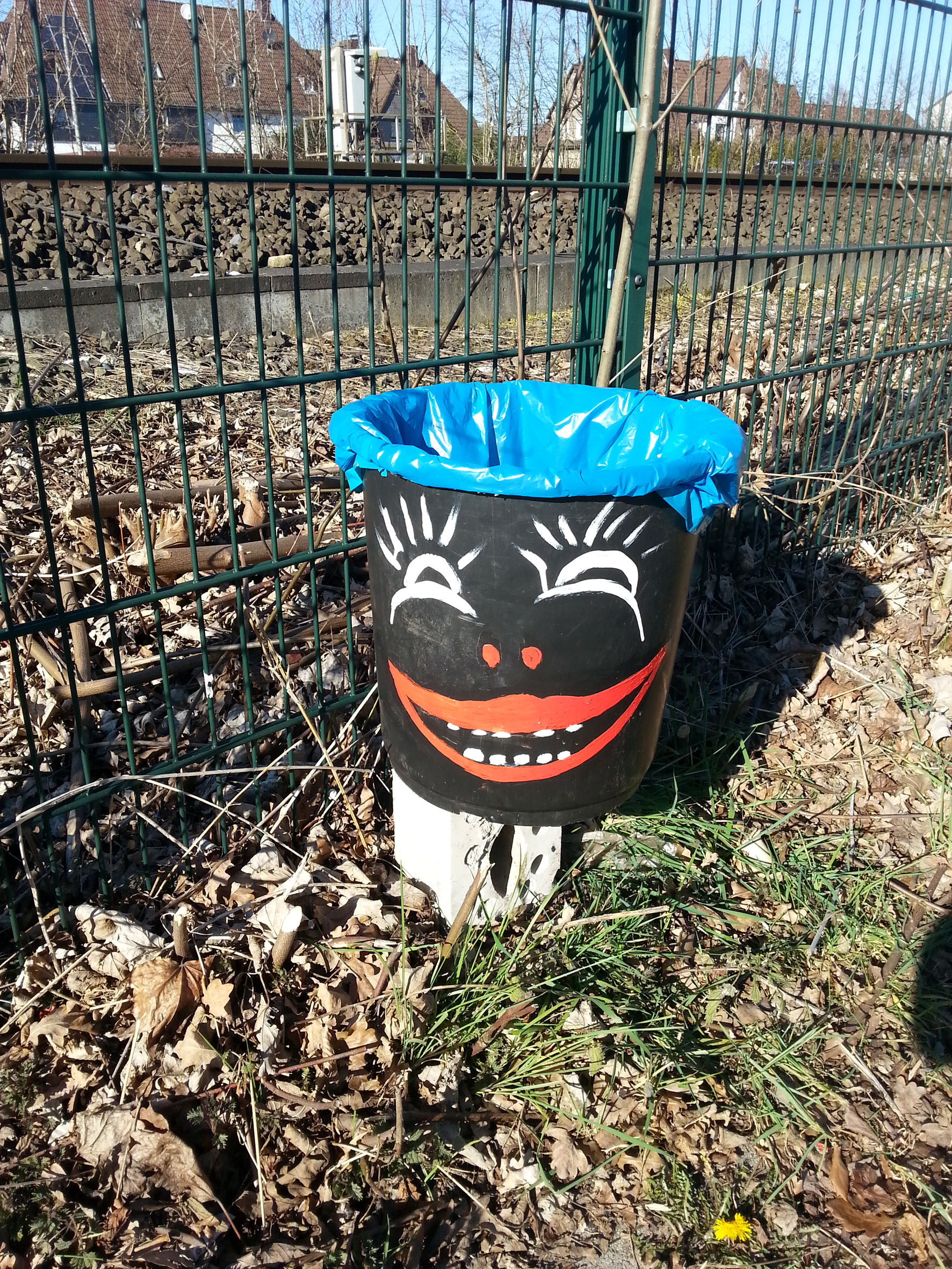 Eine der Self-Made-Mülltonnen steht direkt am Zaun vor dem Bahngelände...
