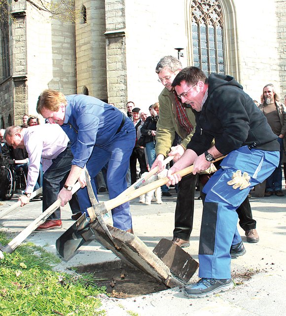 Mit vereinten Kräften hebeln Pfarrer Jörg-Uwe Pehle (r.) und Kirchmeister Uwe Dräger die erste Betonplatte aus dem Pflasterverbund. Sieben Monate lang wird der Kirchplatz rund um die Stadtkirche in Unna nun Baustelle sein. | Foto: Kirchenkreis Unna