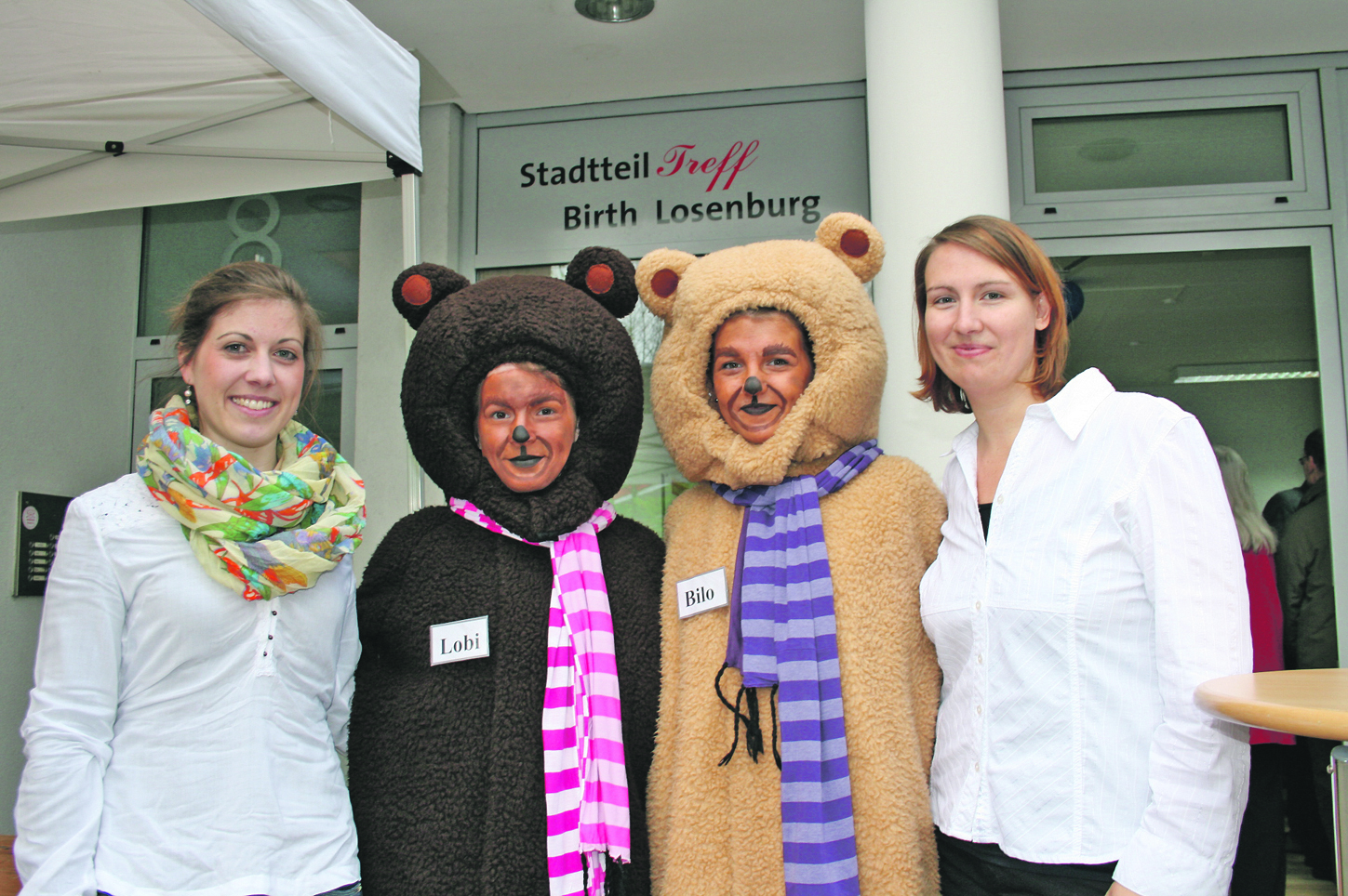 Johanna Springorum (von links), die Stadtteil-Maskottchen „Lobi“ und „Bilo“ sowie Melanie Bundrock vor dem Stadtteiltreff Birth/Losenburg.