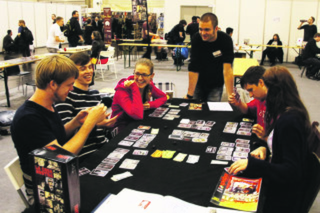 Mit Spaß bei der Sache sind diese Testspieler, die auf der Spielemesse in Essen unter Anleitung von Spielautor Johannes Sich (stehend) „La Cosa Nostra“ ausprobieren.Foto: PR