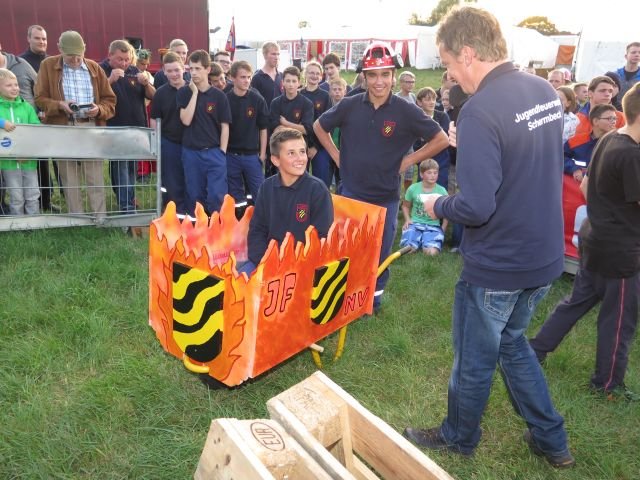Die Schubkarrentruppe mit Spaßhelm auf dem Kopf des Schubkarrenführers