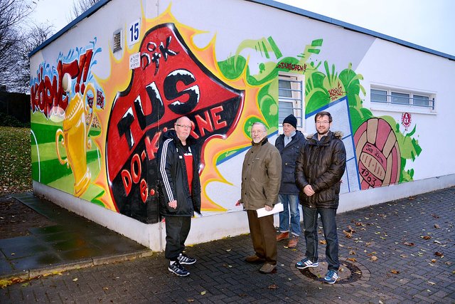 TuS-Vorsitzender Jürgen Kruschka (l.) ist stolz: Passend zum neuen Kunstrasenplatz hat der TuS Körne jetzt auch ein künstlerisch ansprechend gestaltetes Vereinsheim Am Zippen: Graffiti-Künstler Friedrich Lohmeier (r.) hat das vom Körner Kultur- und Kunstverein um Chef Helmut Feldmann (2.v.l.) und Schatzmeister Dieter Rosenbaum finanzierte Groß-Graffito geschaffen, nicht das erste in Körne. - Doch mitten im Ort am Hellweg springen einem immer mehr hässliche gesprühte Graffiti-Tags ins Auge.