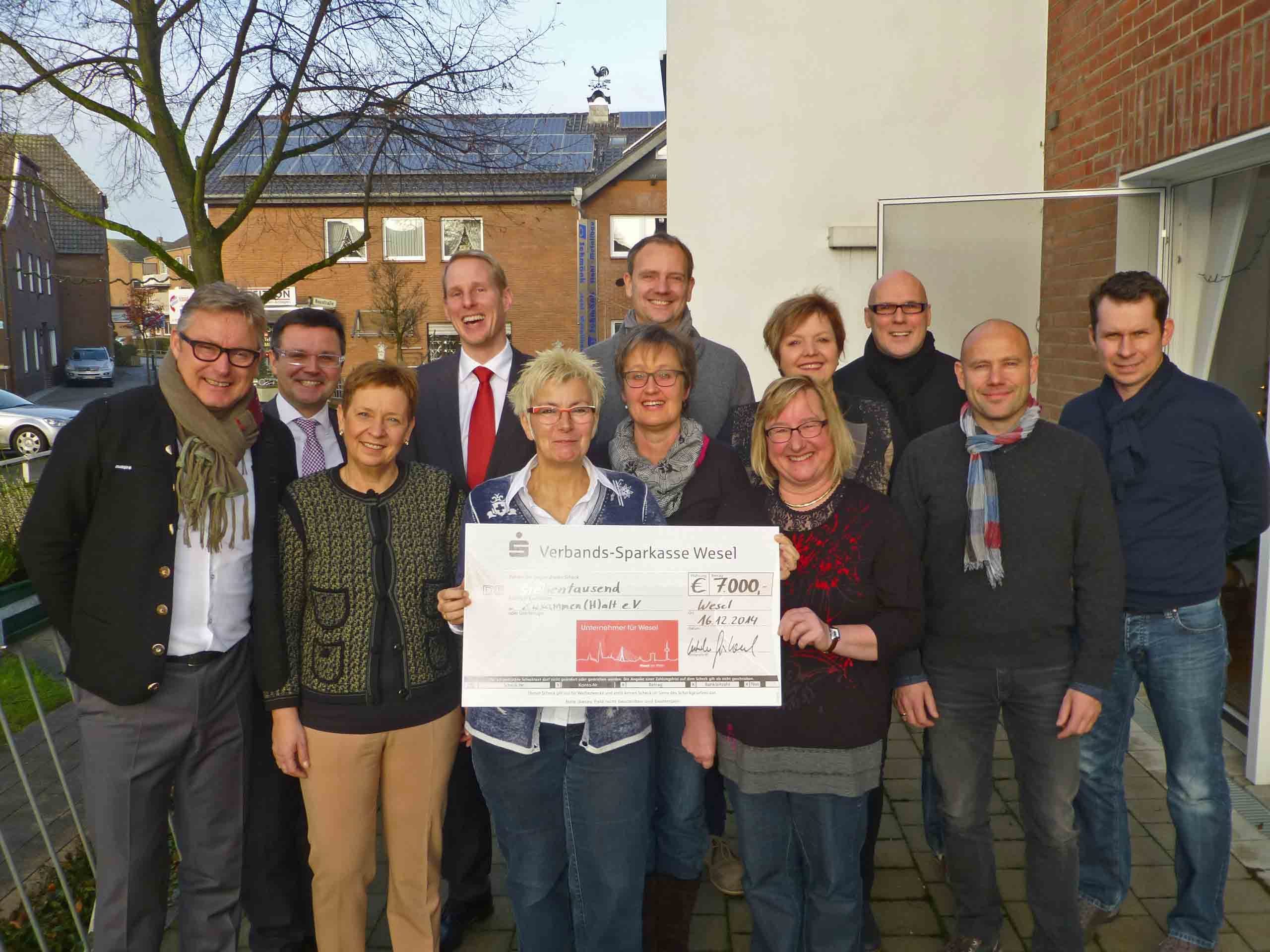 Bildmitte hinterm Scheck: Gudrun Eifert, Claudia Sweers, Angelika Floß (vlnr), umringt von den Verantwortlichen Unternehmern für Wesel