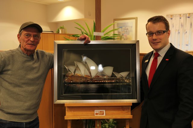 Geschäftsstellenleiter Grischa Klawe präsentiert mit Foto-Künstler Heinz Lappe eines der Bilder der Ausstellung.