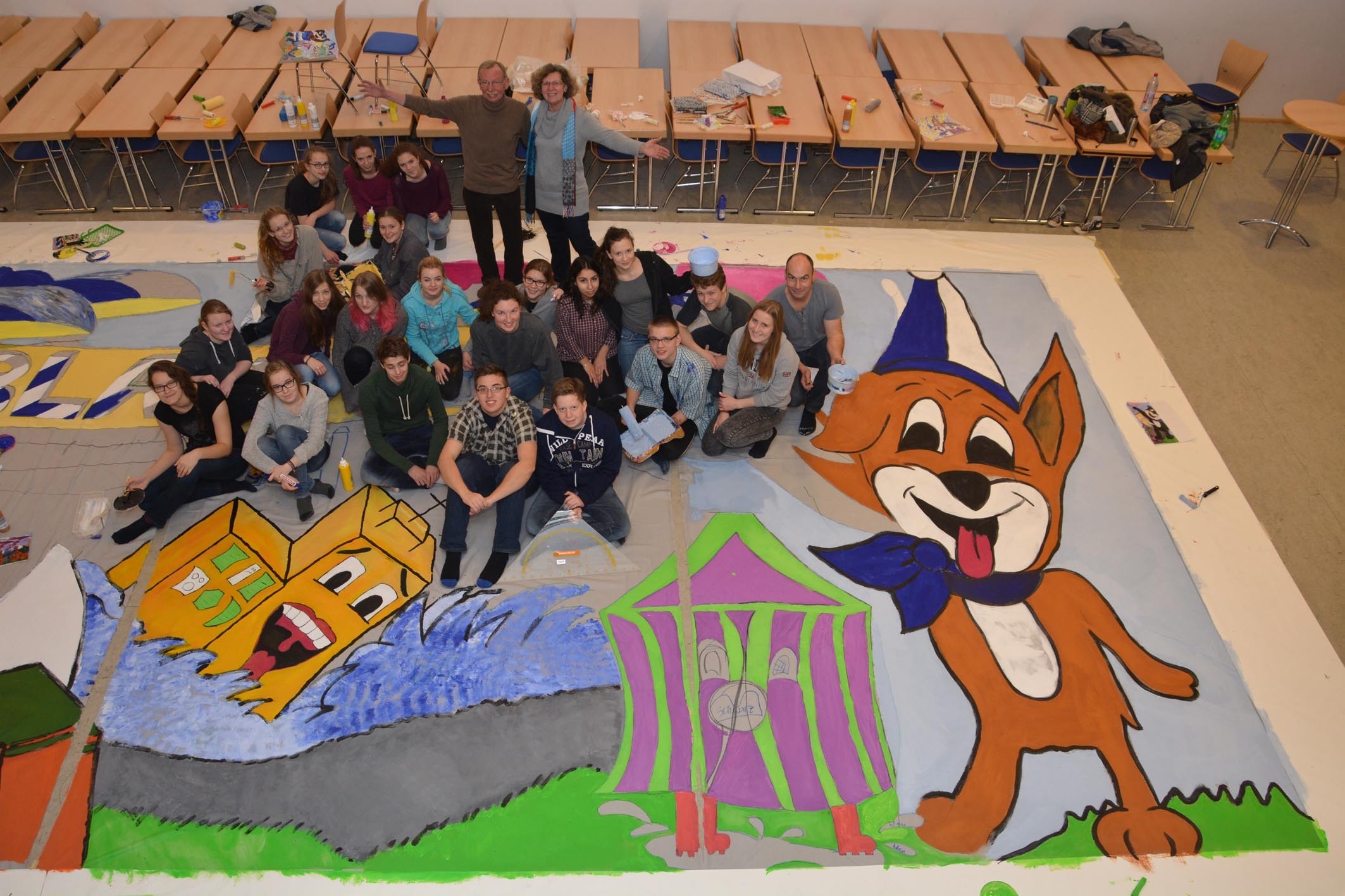 Die Schülerinnen und Schüler aus dem Kunst-Kurs „Q1“ von Kunstlehrer Haimo Hieronymus (re.) am Neheimer St. Ursula-Gymnasium malten in den letzten Stunden des Jahres 2014 das neue, große Bühnenbild, das den Hintergrund im Neheimer Kaiserhaus bei den nächsten Punksitzungen der KG Blau-Weiß Neheim bilden soll. Präsidentin Gertrud Franke und Ehrenpräsident Wilfried Franke freuten sich schon bei der Entstehung des Bildes. Fotos: Albrecht
