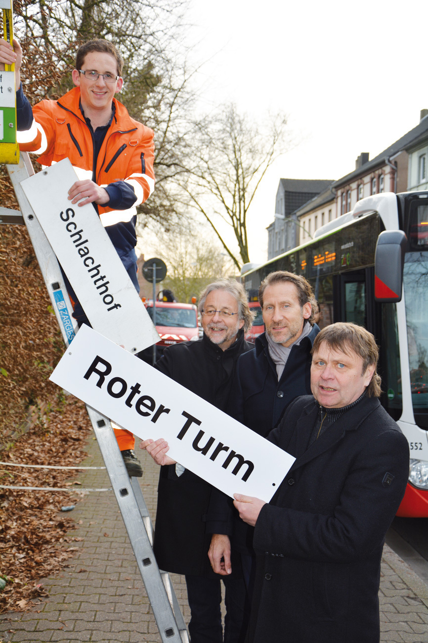 Norbert Konegen, Pressesprecher der Vestischen (v. r.), Frank Purrnhagen, Geschäftsführer der Volksbank Immobilien und Peter Bresser-Barnebeck, Leiter des Referats Wirtschaft und Kommunikation der Stadt Gladbeck, reichen Martin Batschkus von der Vestischen das neue Schild für die Haltestelle.
