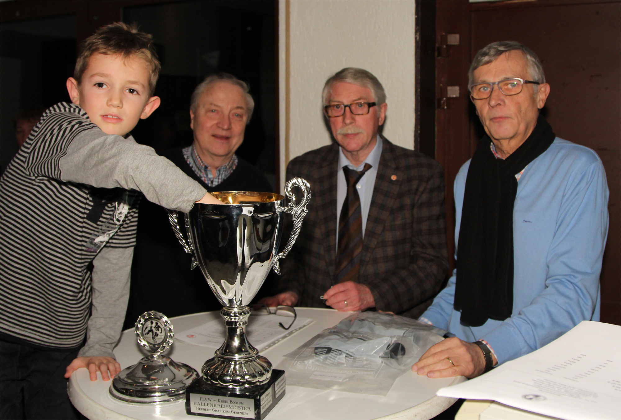 Der 8-jährige Lennox vom Ausrichter DJK Adler Riemke war (v.l.) Gerd Halbherr, Ulrich Jeromin und Bernhard Böning bei der Auslosung behilflich.