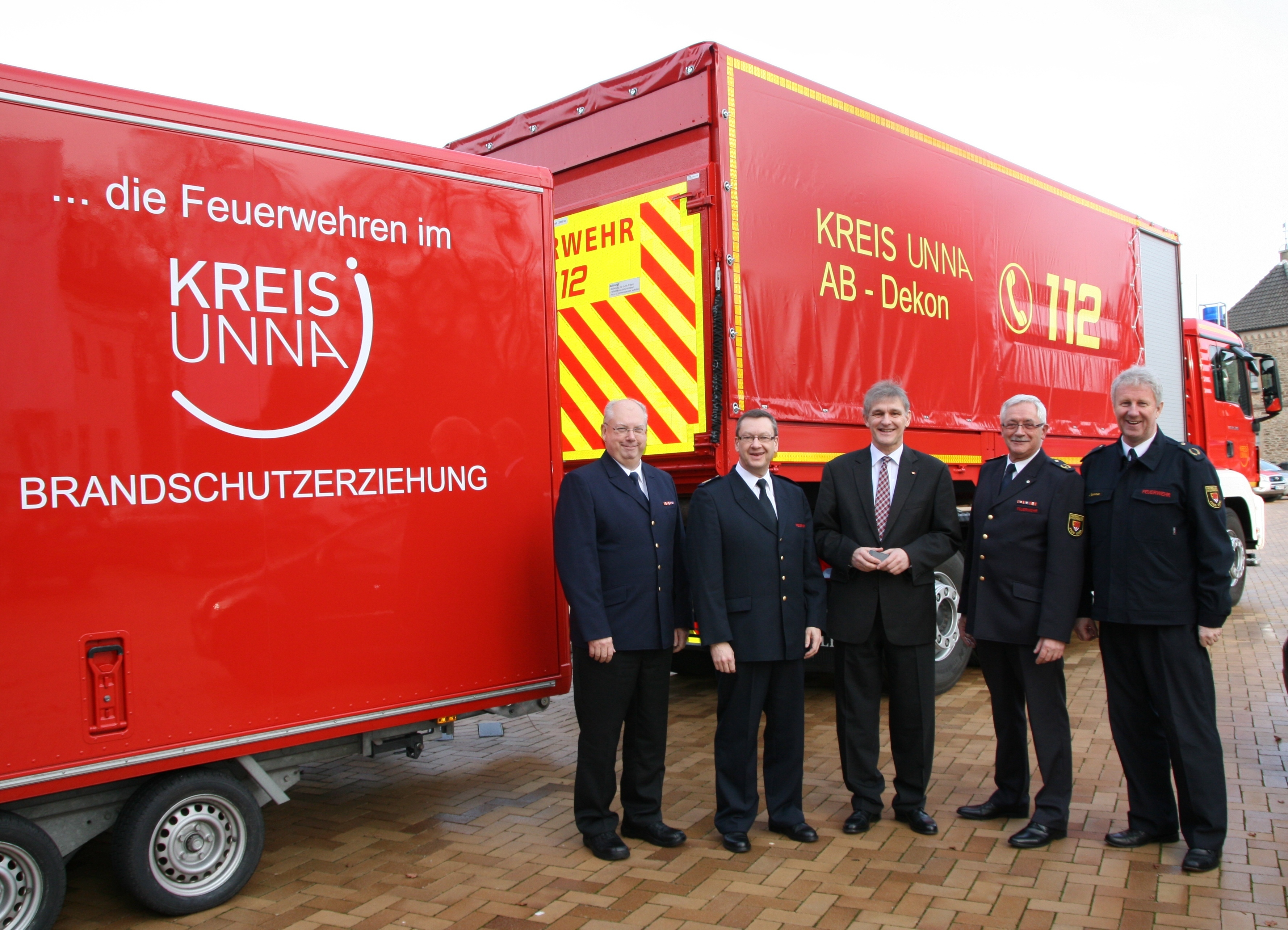 Landrat Makiolla (M.) und Bezirks- sowie Kreisbrandmeister vor dem neuen Abrollbehälter der Feuerwehr. Foto: C. Rauert