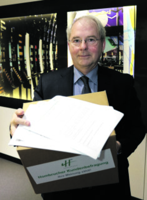 Heinz-Herbert Dustmann mit einer Sammelbox und ausgefüllten Fragebögen.