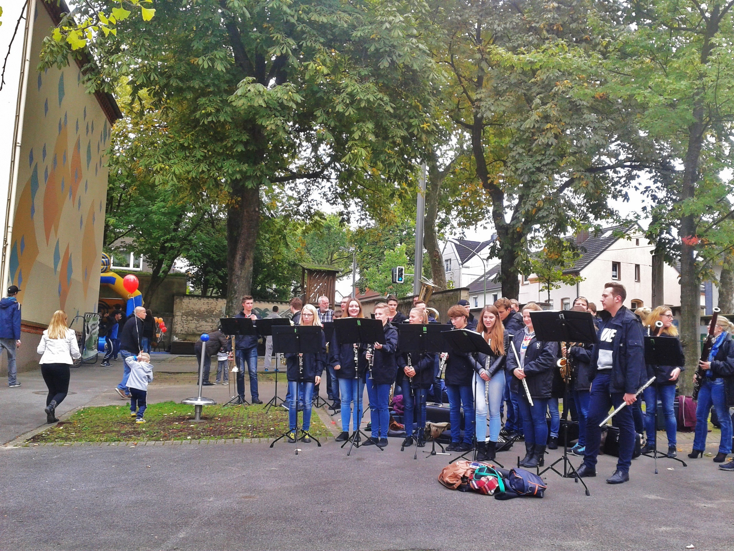 Das Schönebecker Jugenblasorchester im Einsatz auf dem Schulhof im Neerfeld. Flüchtlinge wie Einheimische brauchen gute Musik, wenn sie den schweren Alltag in der Woche fröhlich überstehen wollen - gemeinsames Klatschen hilft immer.