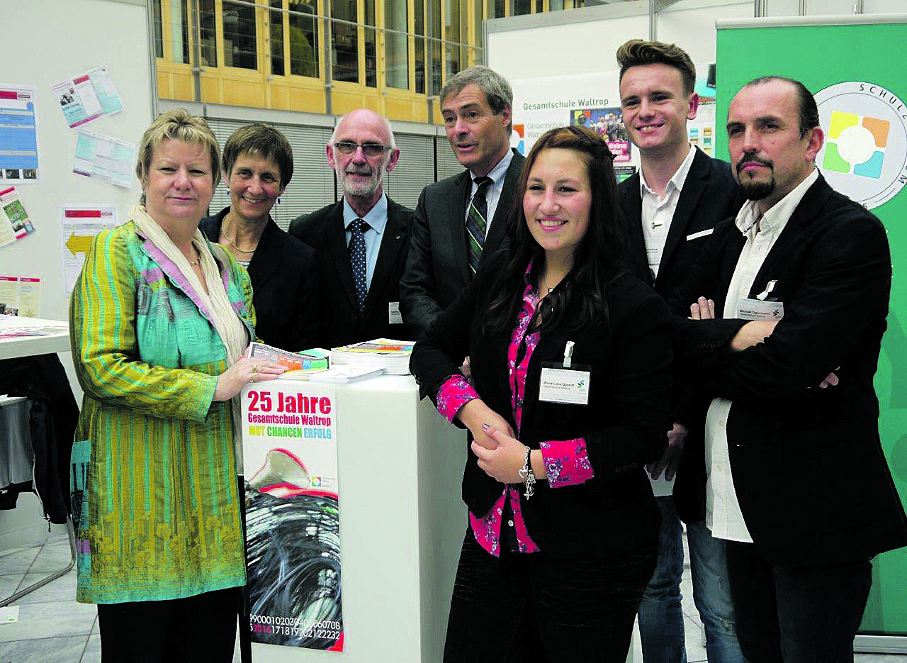 Ministerin Sylvia Löhrmann, Schulleiterin Ulrike Waterkamp, Projektleiter Hartmut Nürnberg, Arbeitgeberpräsident Ingo Kramer, Anna-Lena Quandt, Fabian Vathauer und Michael Ogiermann (v.l.) am Expo-Stand NRW im Haus der Deutschen Wirtschaft.