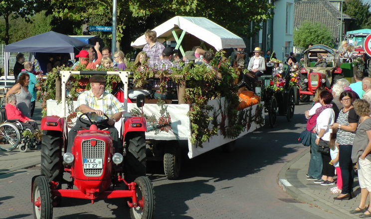 Bunte Wagen Fahrrad- und Fussgruppen ziehen beim Erntedankzug mit