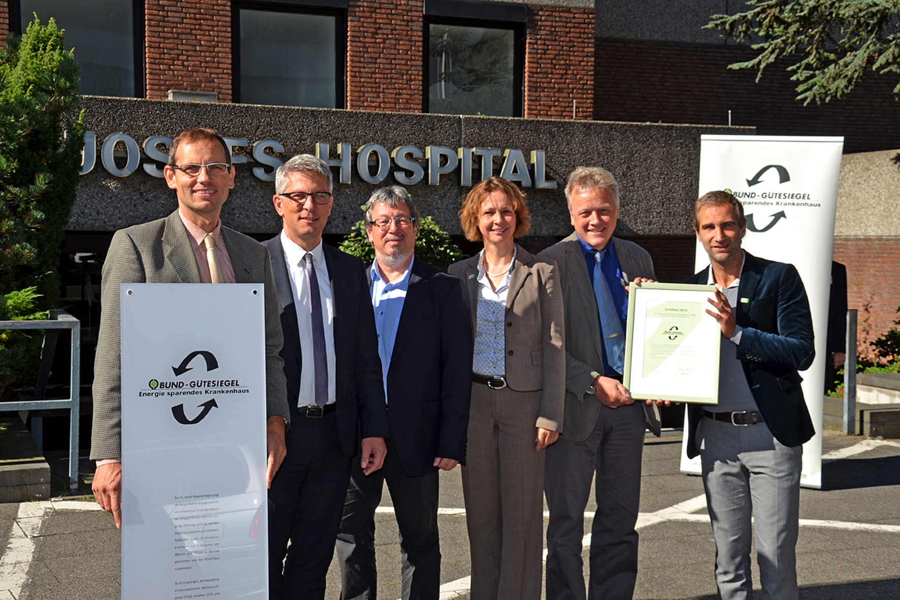 Stellvertretend für alle Mitwirkenden und Beschäftigten der Klinik empfangen Herr Brenneis und Herr Lorke, Technischer Gesamtleiter, die Gütesiegel-Urkunde von Holger Sticht und Annegret Dickhoff, Projektleiterin.