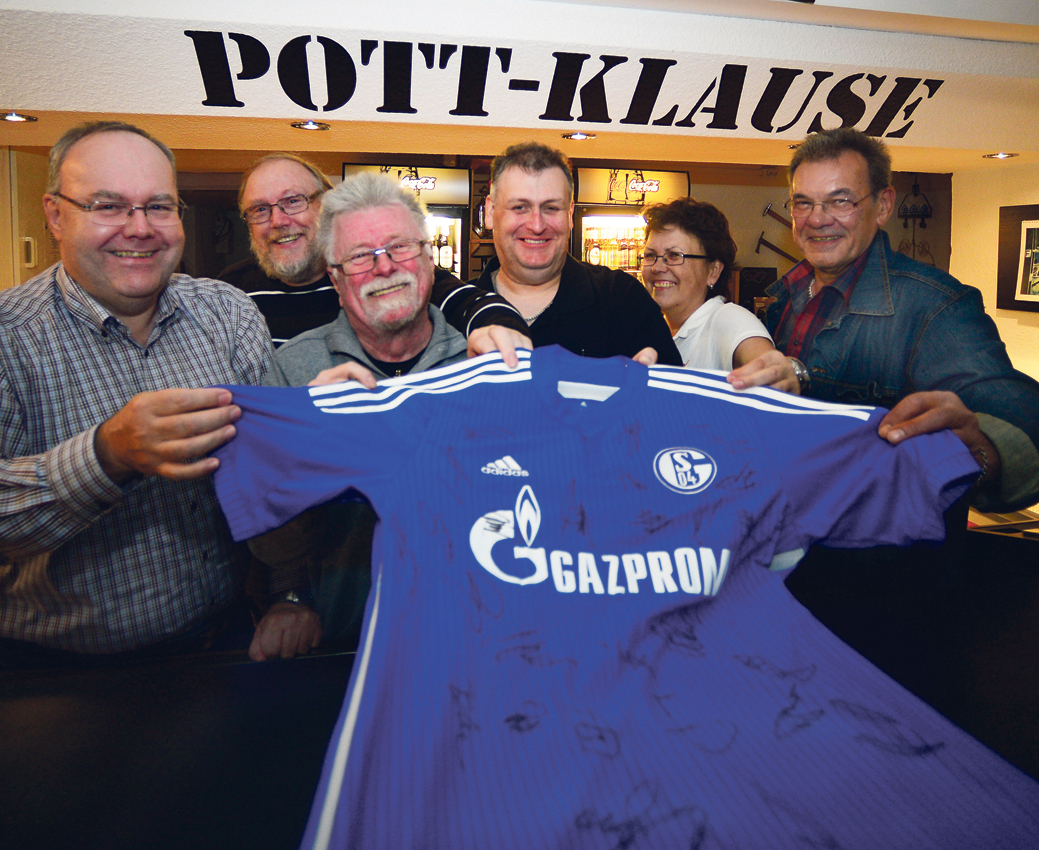 Die Mitglieder des Anglervereins „AV Pinn -Wipp Scholven 1972“ mit dem Schalke-Trikot, das zur Versteigerung auf einen neuen Besitzer wartet: Von links – Achim Wroben, Jürgen Fürstenau, Vorsitzender Jürgen Moskon, Gewässerwart Thomas Wollbrink, Vereinswirtin Martina Siegert und Siegfried Luck.