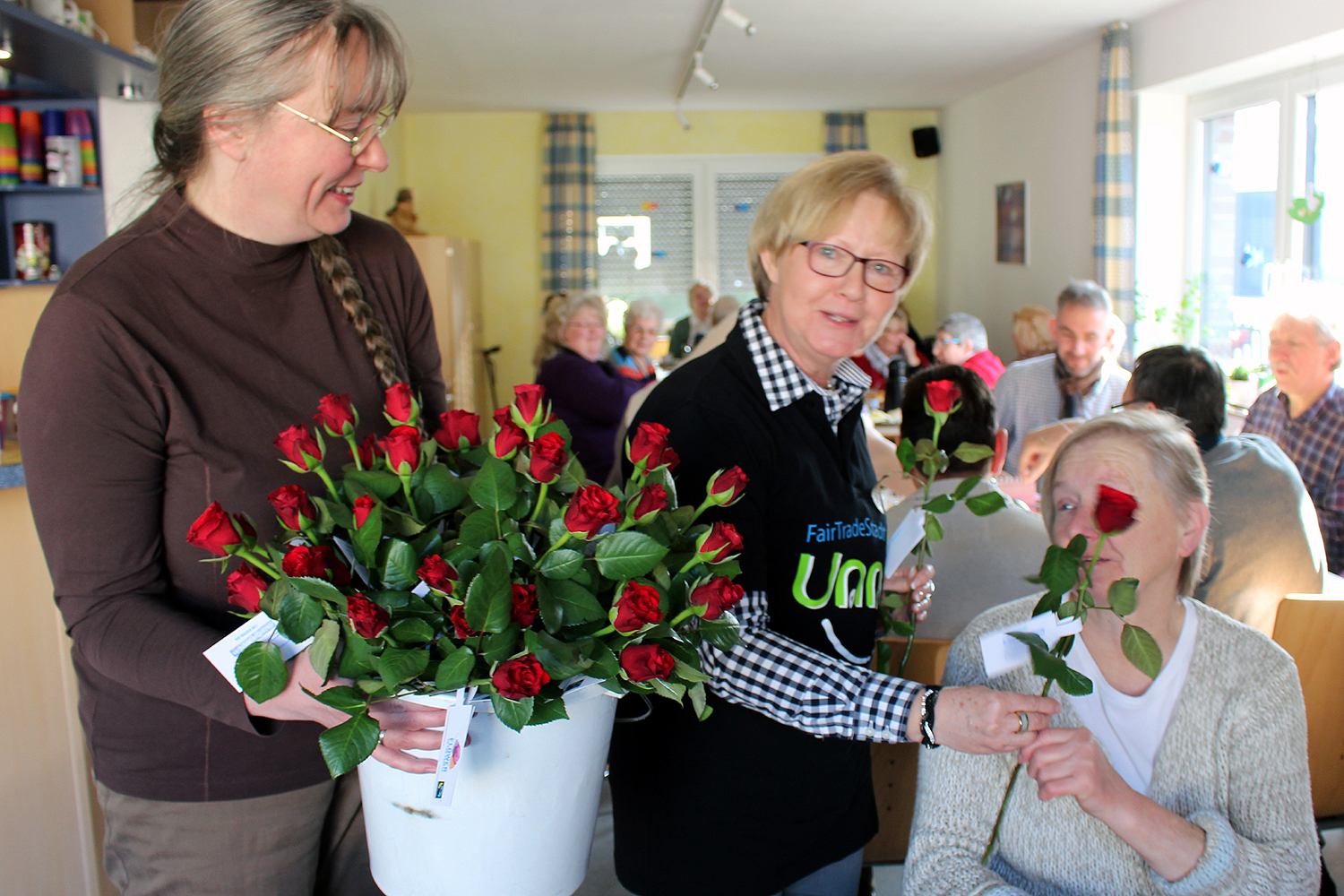 Sabine Schulze (Gemeindebüro Ev. Kirchengemeinde), Gabriele Floegel (Ev. Kirchengemeinde und Fairtrade Unna) überbringen Rosen zum Frühstück „Morgensonne“