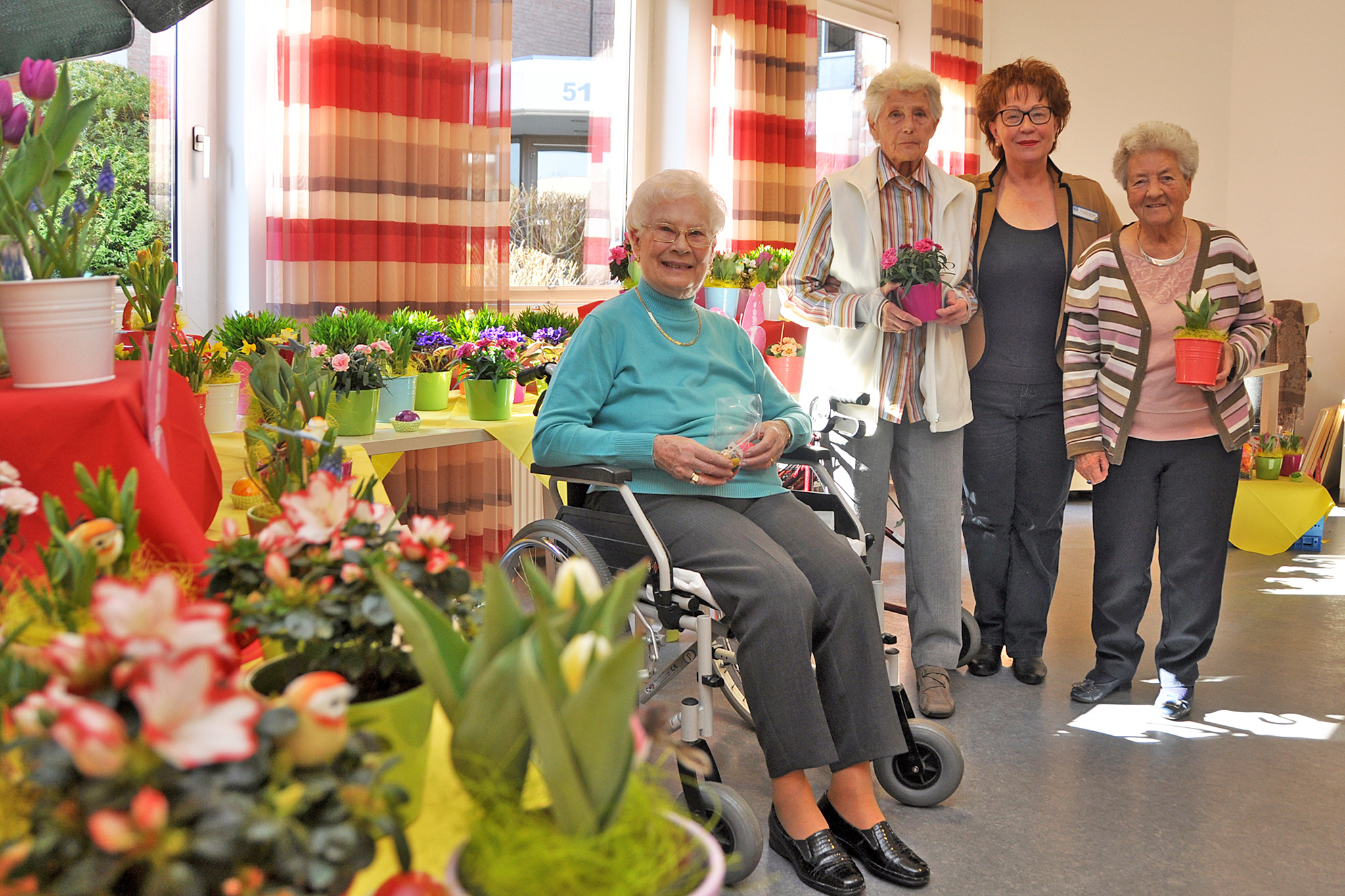 (v.l.) Bewohnerinnen Ruth Plüme, Marianne Schäfer und Gerti Heinze lassen sich von Magarete Szumigala (3. von links) über das Blumenmarkt-Angebot aufklären.