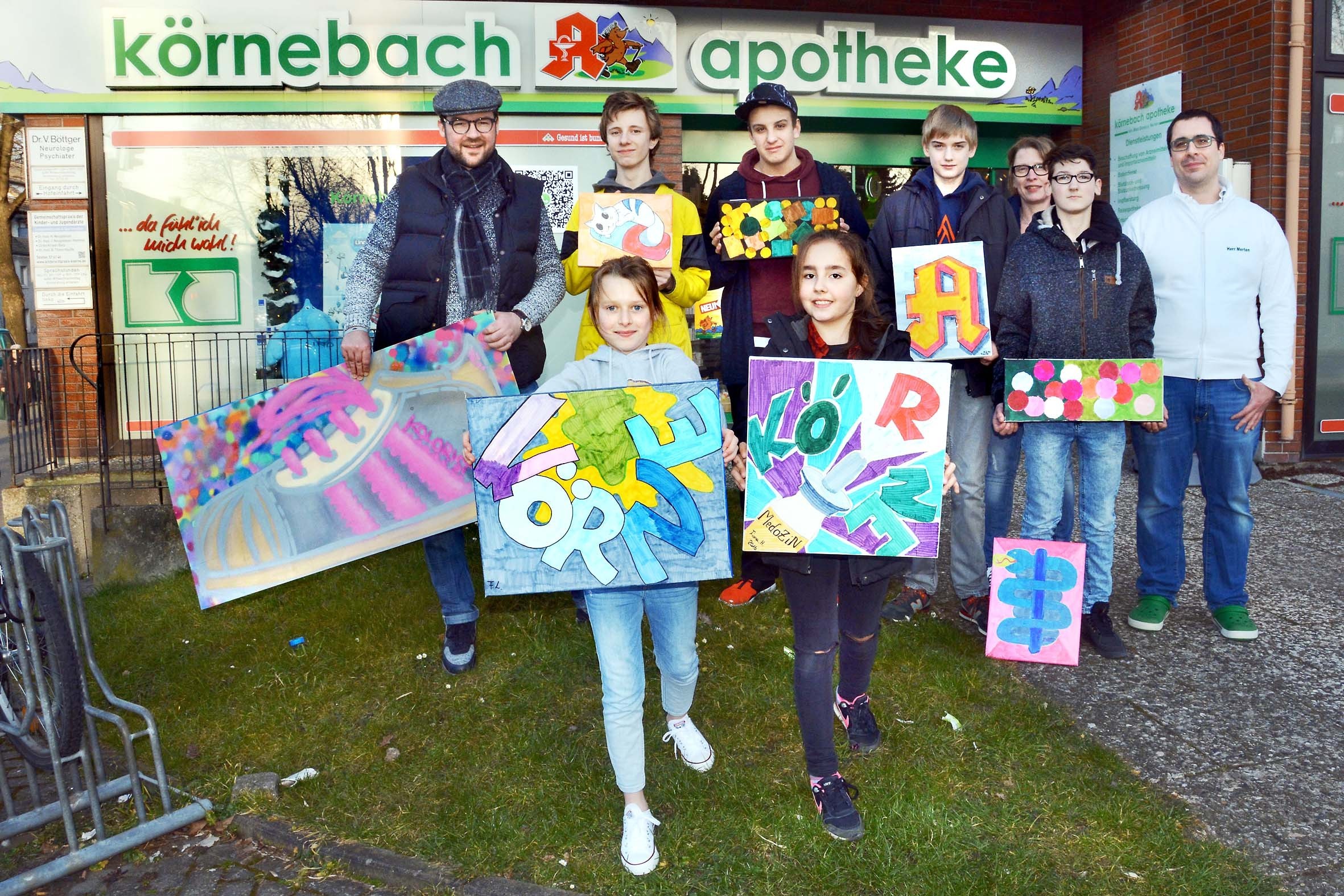 Die jungen Künstler der Jugendfreizeitstätte Winkelriedweg haben mit Künstler Peter Lohmeier (l.) und Leiterin Andrea Kohls (3.v.r.) für ihre Ausstellung in der Körnebach-Apotheke von Inhaber Marc Dominic (r.) viele phantasievolle Graffiti-Werke geschaffen.