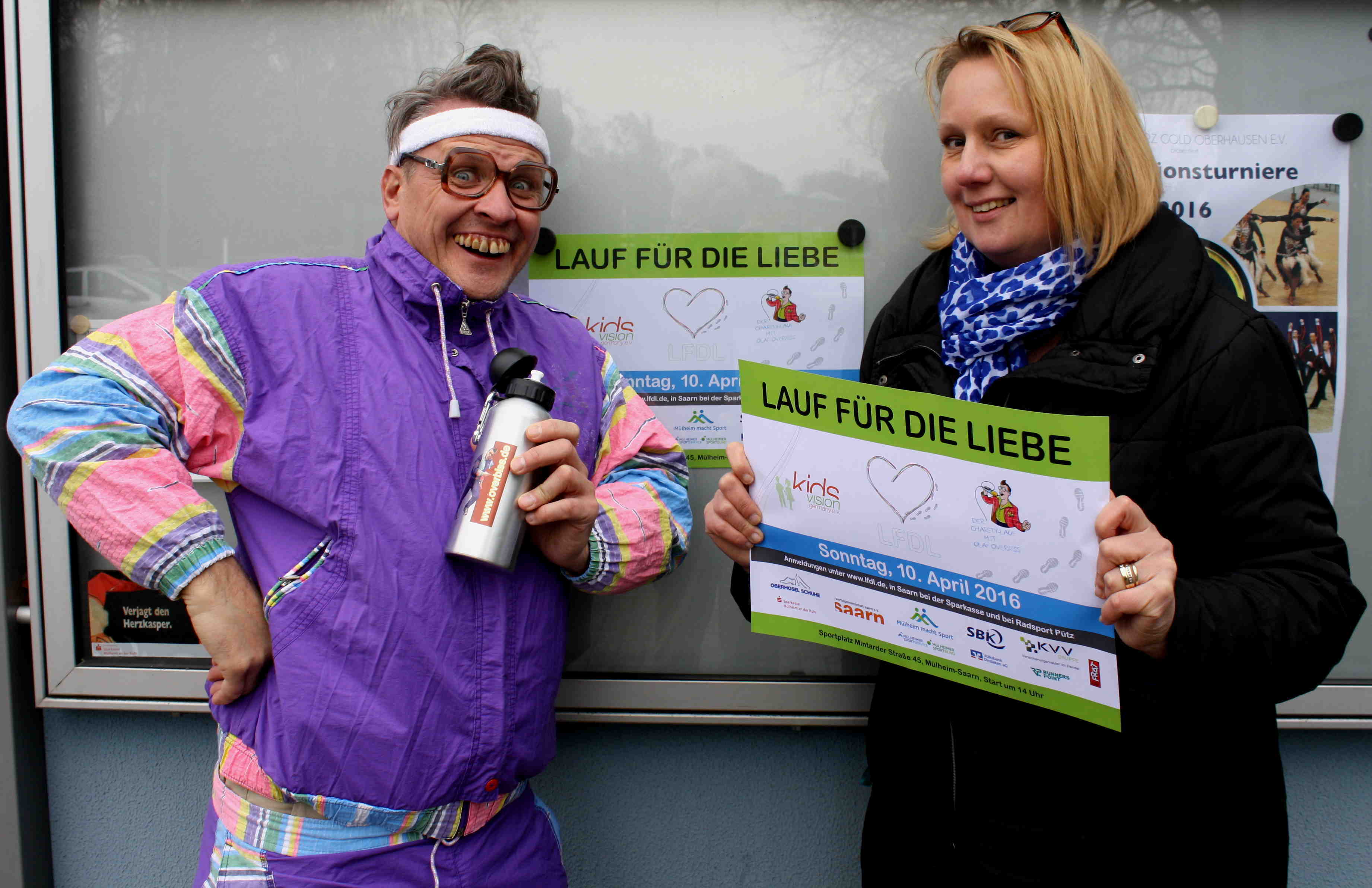 Margit Schettler von der Saarner Werbegemisnchaft als Ausrichter präsentiert das Veranstaltungsplakat und Roland Donner alias "Olaf Overbiss" der Comedian werben für den Lauf der Liebe.