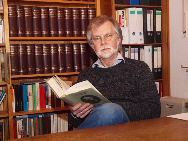 Dr. Bernd Schminnes blättert in einem historischen Buch.