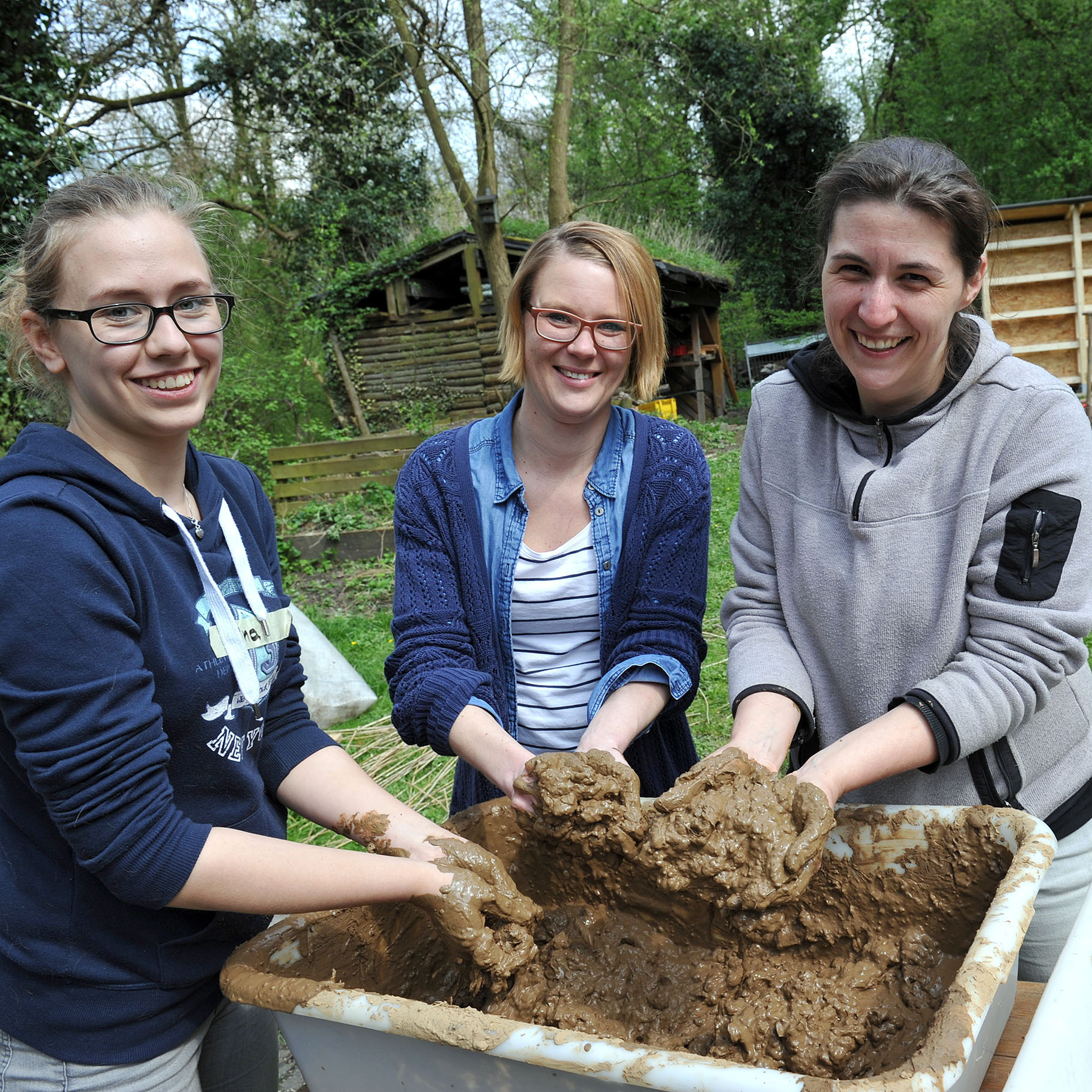 Sina Kordgis, Catrin Nickel (Klassenlehrerin) und Vanessa Burneleit, Vorsitzende der NAJU, (v.l.) durchmengen den Lehm für das Insektenhotel. Fotos: Debus-Gohl