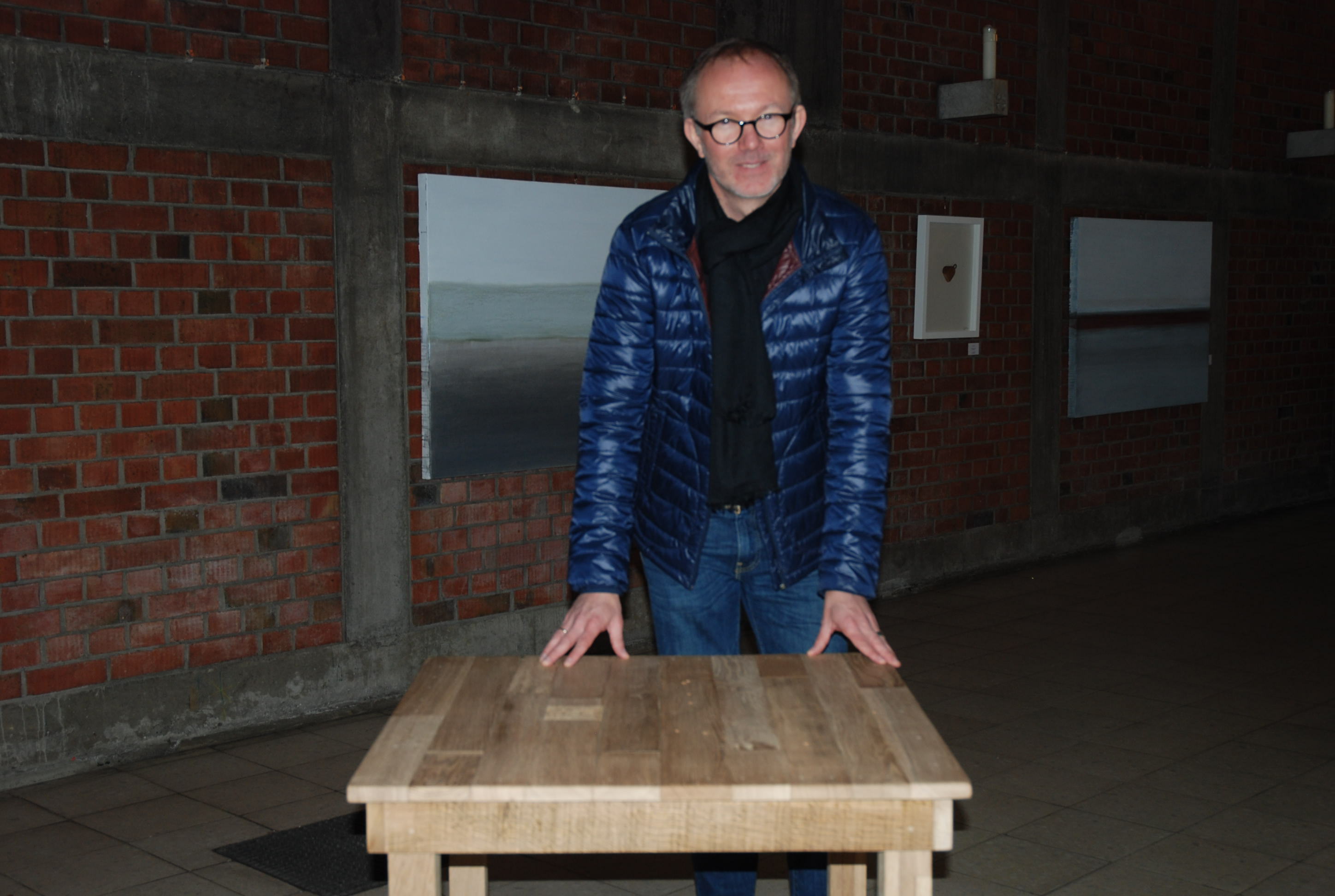 Mirko Stefan Elfert vor seinem Holztisch, gefertigt aus hölzernen Kreuzen.