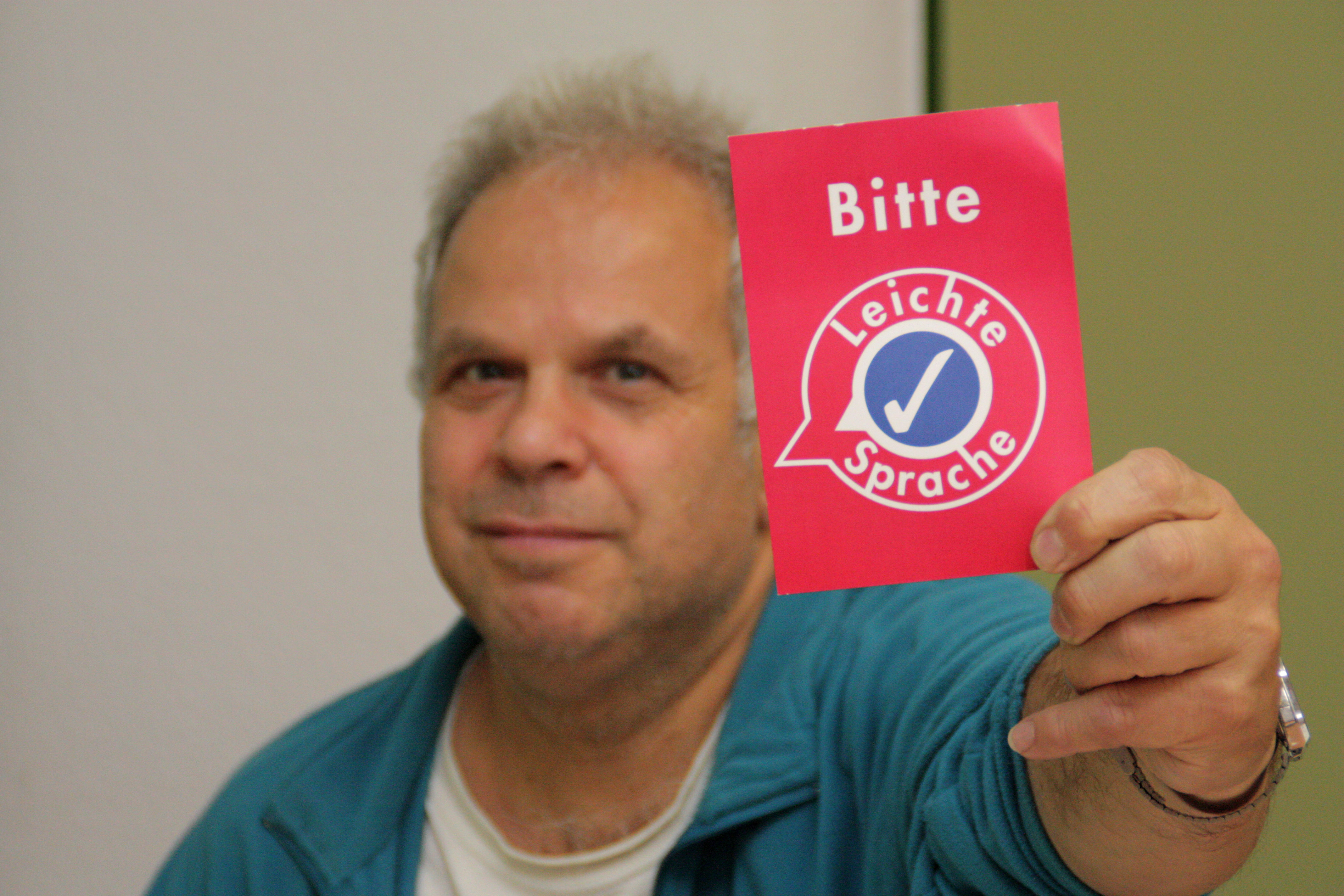 Werkstatt-Beschäftigter Rainer Rosenlöcher nutzt eine rote Karte, um zu zeigen, dass er etwas in einem Text nicht verstanden hat. „Bitte Leichte Sprache“, wünscht er sich.
