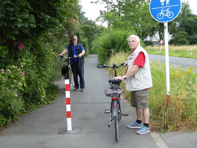 Von beiden Seiten wuchert das Grün den kombinierten Rad-/Gehweg entlang der Wickeder Straße langsam zu. Radler und Fußgänger können sich kaum mehr begegnen, weiß auch Anwohner Wolfgang Spieß (r.), zudem schirmt das Grün die Beleuchtung im Dunklen ab.