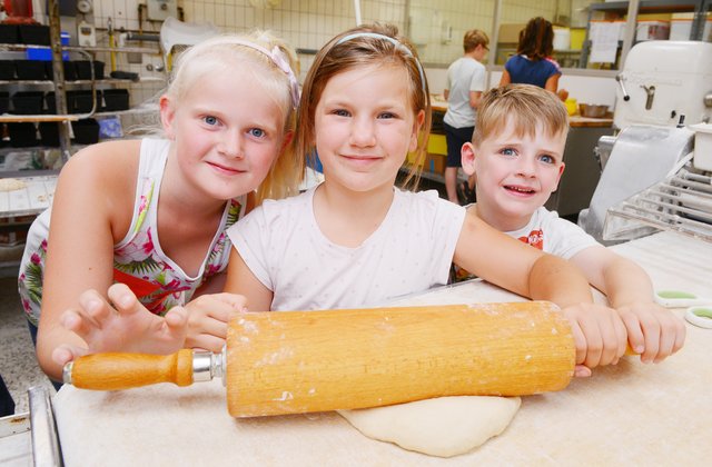 Nele, Pia und Linus wollen den Teig erst einmal rollen, bevor sie sich an das Kneten und Formen machen. Foto: de Clerque