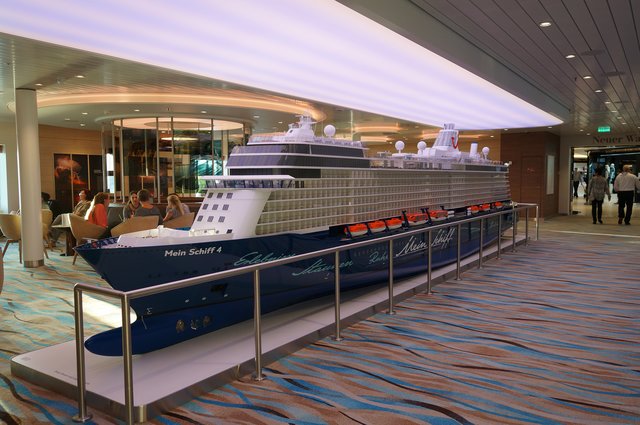 Auf Deck 4, neben der Waterkant-Bar, steht dieses Mein-Schiff-Modell. Es wiegt ca. 1 Tonne. Auf der nicht sichtbaren Seite werden Videos zum (Berufs-)Alltag auf dem Schiff gezeigt (Wäscherei, Großküche ....)