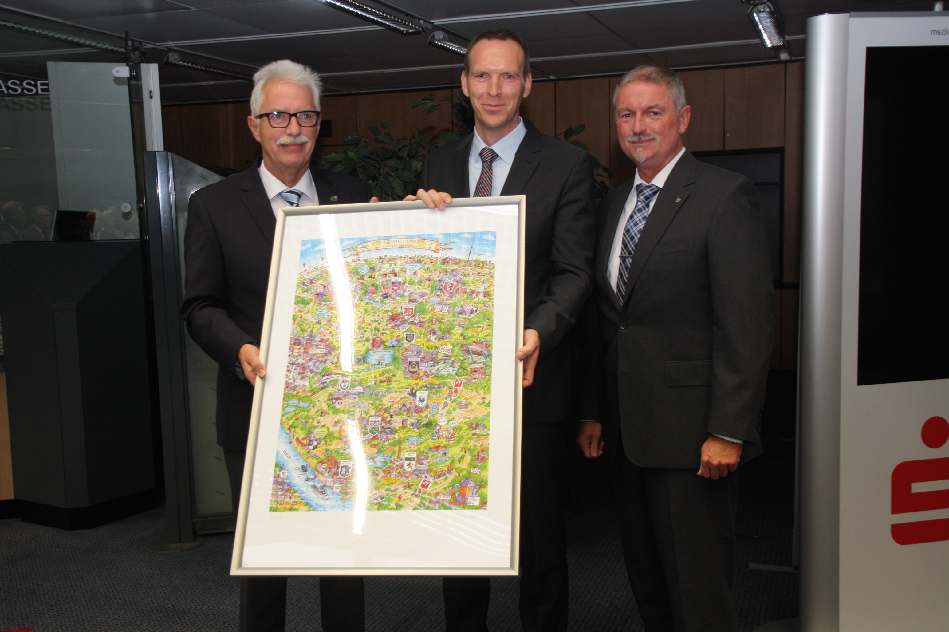 Landrat Thomas Hendele überreichte das Wimmelbild von Jacques Tilly an Bürgermeister Doktor Jan Heinisch. Rechts Kämmerer Michael Beck. Foto: PR