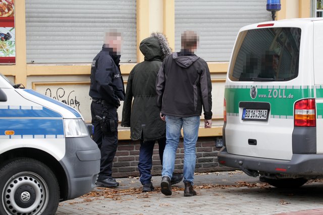Polizisten führen den Verhafteten zu einem der Streifenwagen. | Foto: Magalski