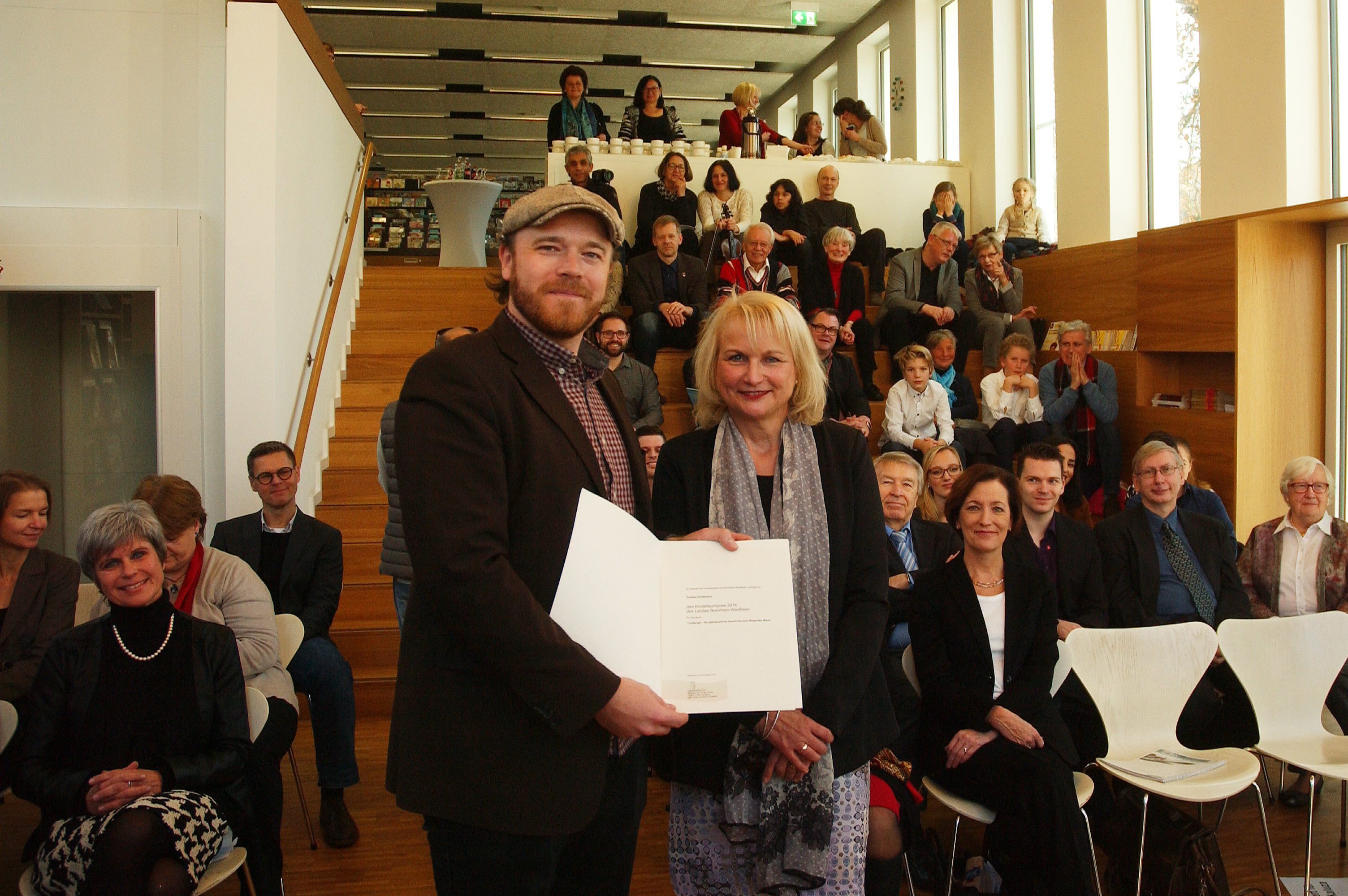 Torben Kuhlmann nimmt den Kinderbuchpreis des Landes NRW von Dr. Hildegard Kulazza vom Ministerium für Familie, kinder, Jugend und Sport entgegen.